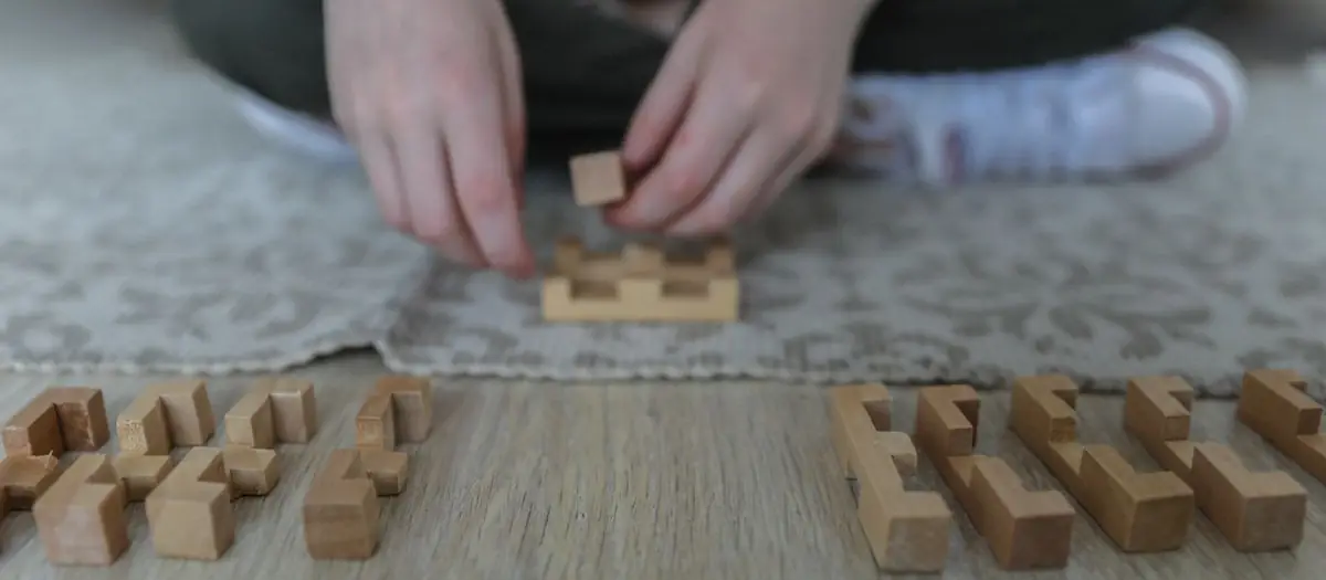 Niña jugando con bloques de madera sobre una alfombra