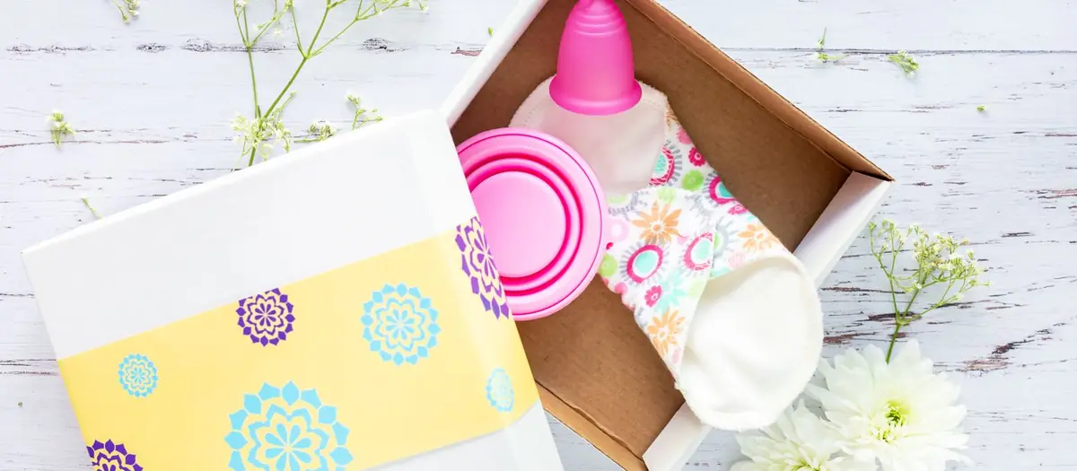 Copa menstrual en su caja, junto a flores