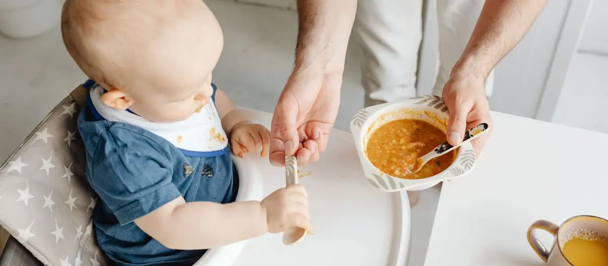 Padre dando de comer a su bebé con cuchara
