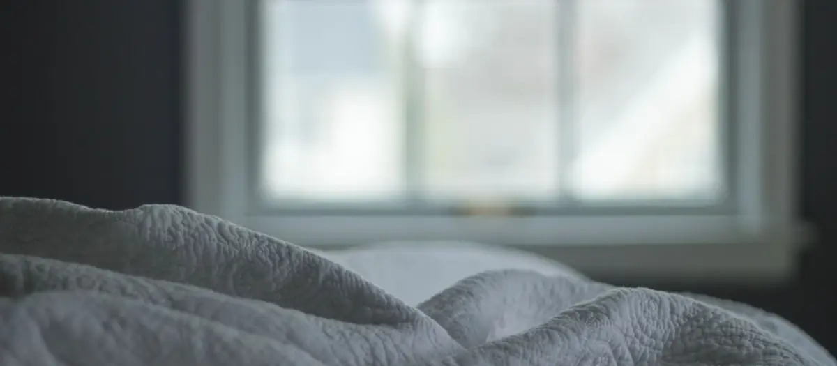 Cama deshecha junto a una ventana