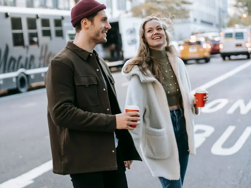 Pareja caminando por la calle con café para llevar